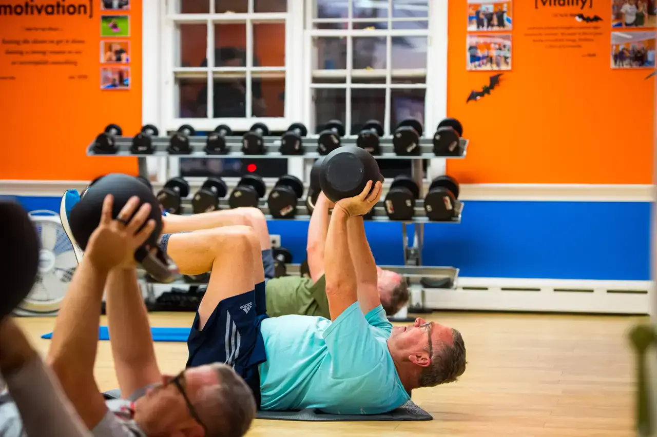 Two members pressing dumbbells side by side